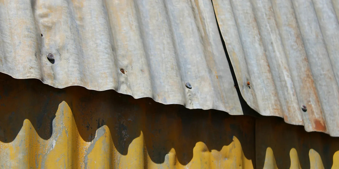 Weathered corrugated steel roof sheeting with rust streaks running from the fasteners