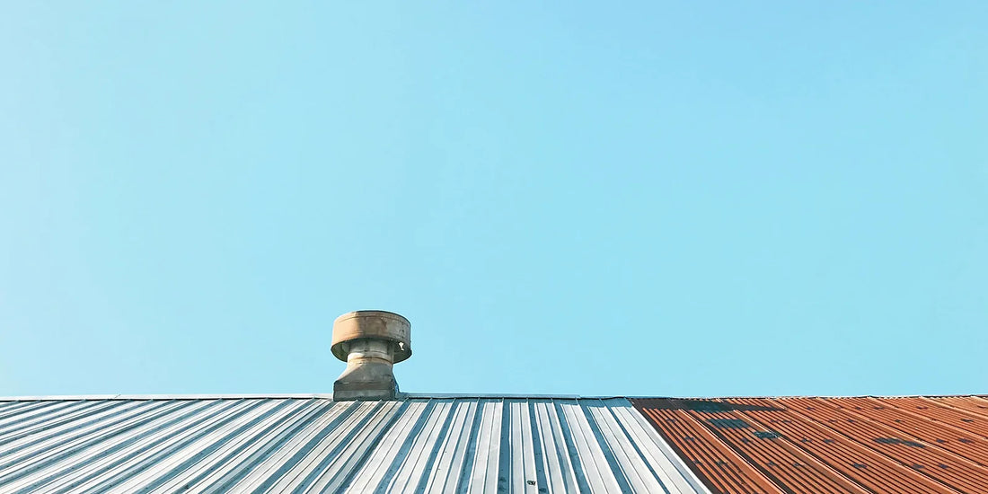 A roof ventilator on a corrugated metal roof against a clear blue sky