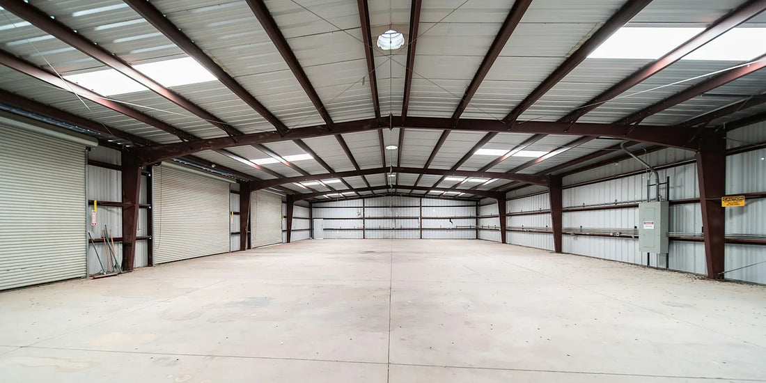 Empty industrial shed interior showing steel portal frames, purlins and roof sheeting