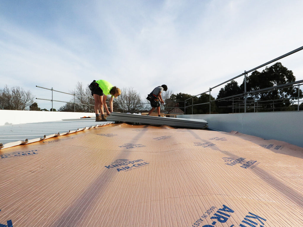 Kingspan AIR-CELL Insulbreak laid across a low pitch roof as roofers fix the metal roof sheets