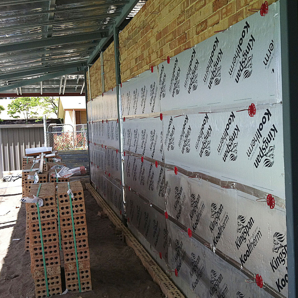 Kooltherm cavity boards fixed to a brick inner leaf with red retaining discs on the wall ties